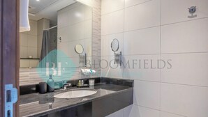 Een moderne badkamer met een zwart aanrecht, witte tegels en twee spiegels.