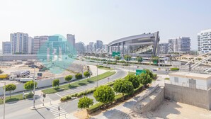 Een modern stadsgezicht met een opvallend gebogen gebouw, waarschijnlijk een stadion, en een weg met een rotonde.