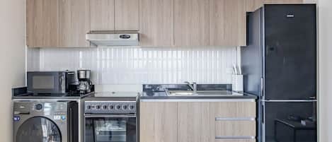 A modern kitchen with wooden cabinets, a built-in microwave, a coffee maker, a stove, an oven, and a refrigerator.