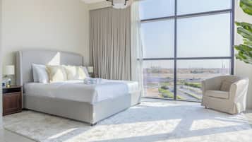 A modern hotel room with a large bed, a sitting area, and a view of the cityscape.