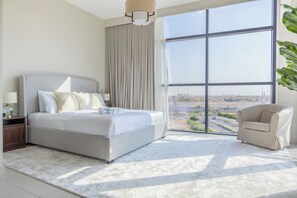 Una moderna camera d'albergo con un ampio letto, una zona salotto e vista sulla città.