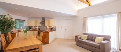 A spacious living area with a wooden dining table and a grey sofa.