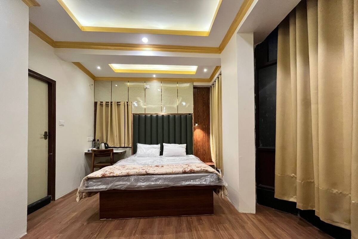 Quarto moderno com cama de madeira, uma escrivaninha e um espelho grande.