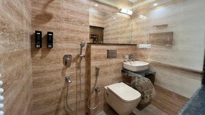 Une salle de bain moderne avec un mur en marbre, des toilettes, un lavabo et une douche dotée de plusieurs robinets.