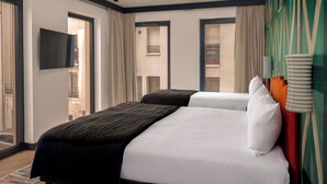 A hotel room with two beds, a flat-screen TV, and a view of the outside balcony. - Chachacha Hôtel (Nantes)