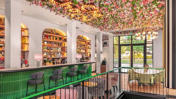 A modern interior with a green bar area, multiple seating options, and a ceiling adorned with flowers and lights. - Chachacha Hôtel (Nantes)