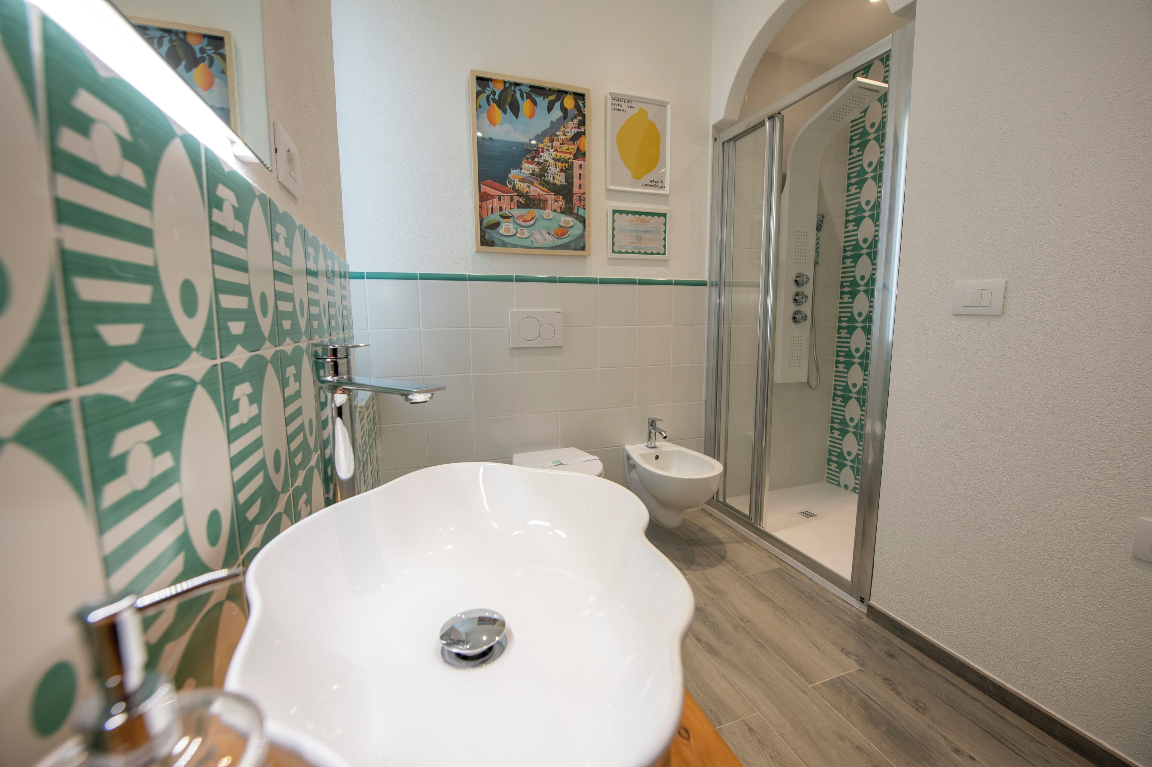A bathroom with a large white sink, a bidet, and a glass shower enclosure.
