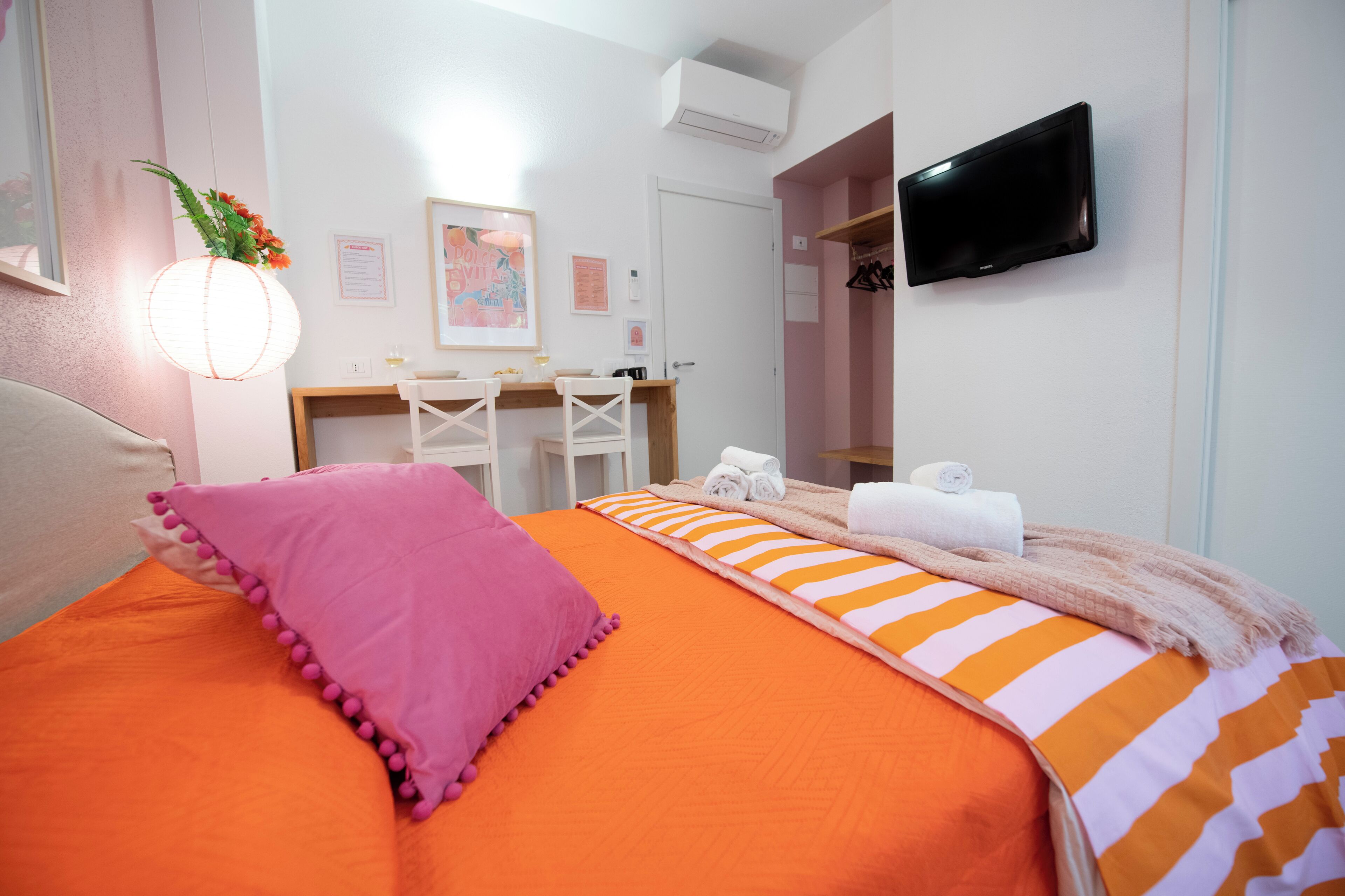 Ett hotellrum med en säng, ett skrivbord, en stol, en tv och ett badrum.