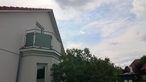 A corner of a building with a red-tiled roof, a white facade, and a window with a metal frame. - Ferienwohnung Kranichring in Negast Nahe Stralsund (Steinhagen)