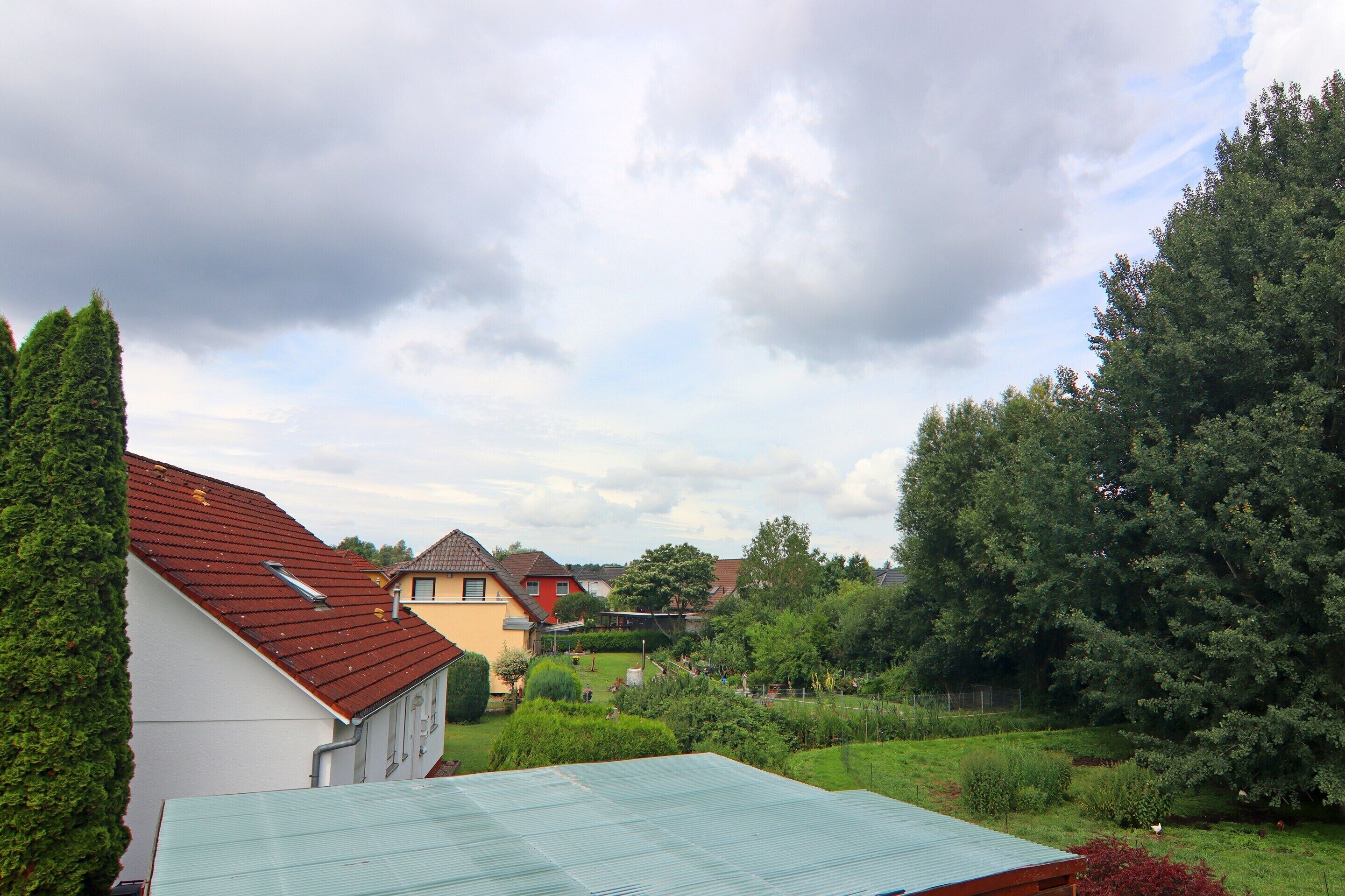 A residential area with houses, a green lawn, and a cloudy sky.