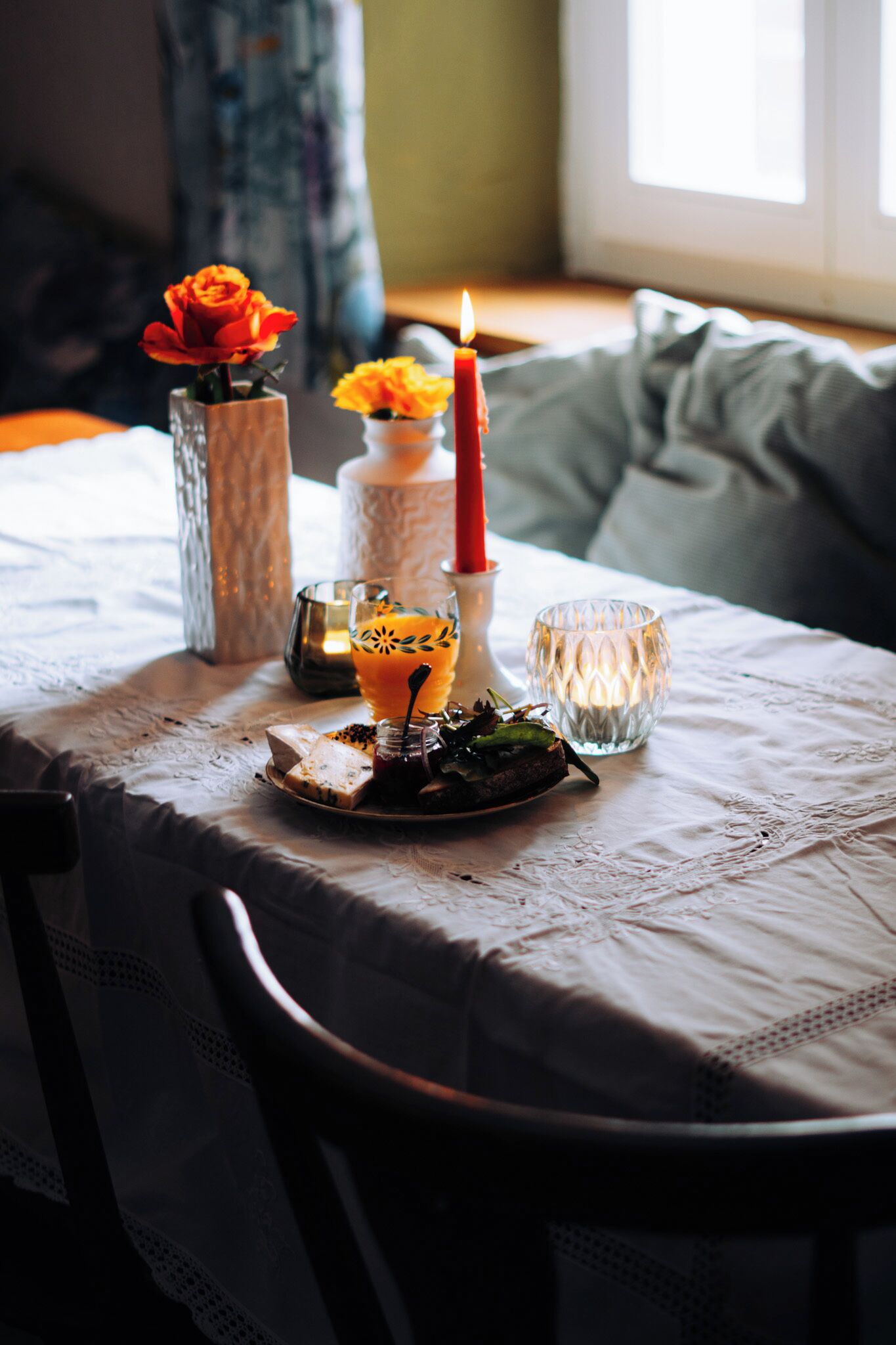 A table set with a candle, a vase with a flower, and a glass with a candle inside.