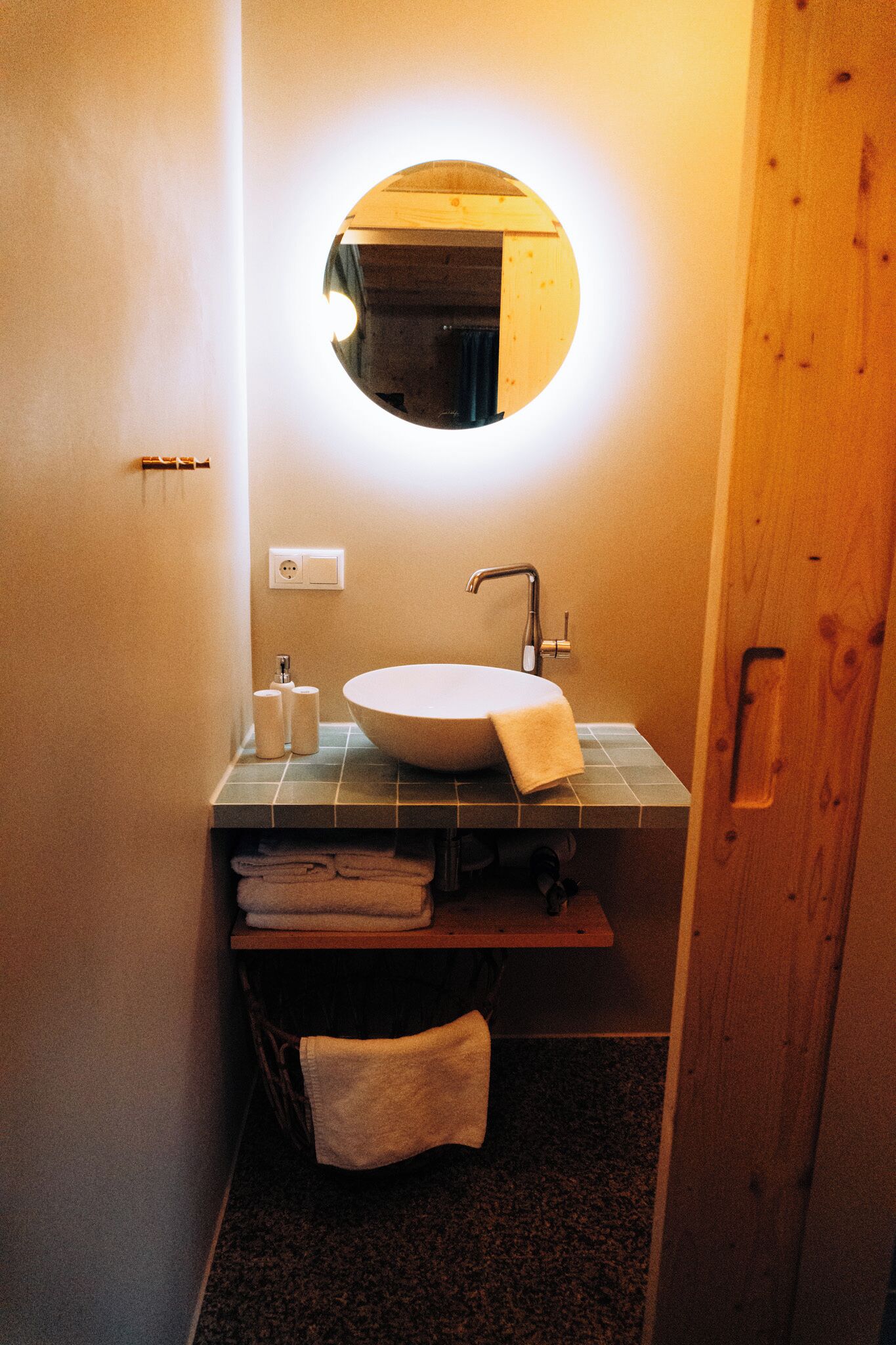 A bathroom with a round mirror, a sink, and a towel rack.