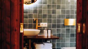 A bathroom with a wooden door, a white sink, a mirror, a towel rack, and a toilet.