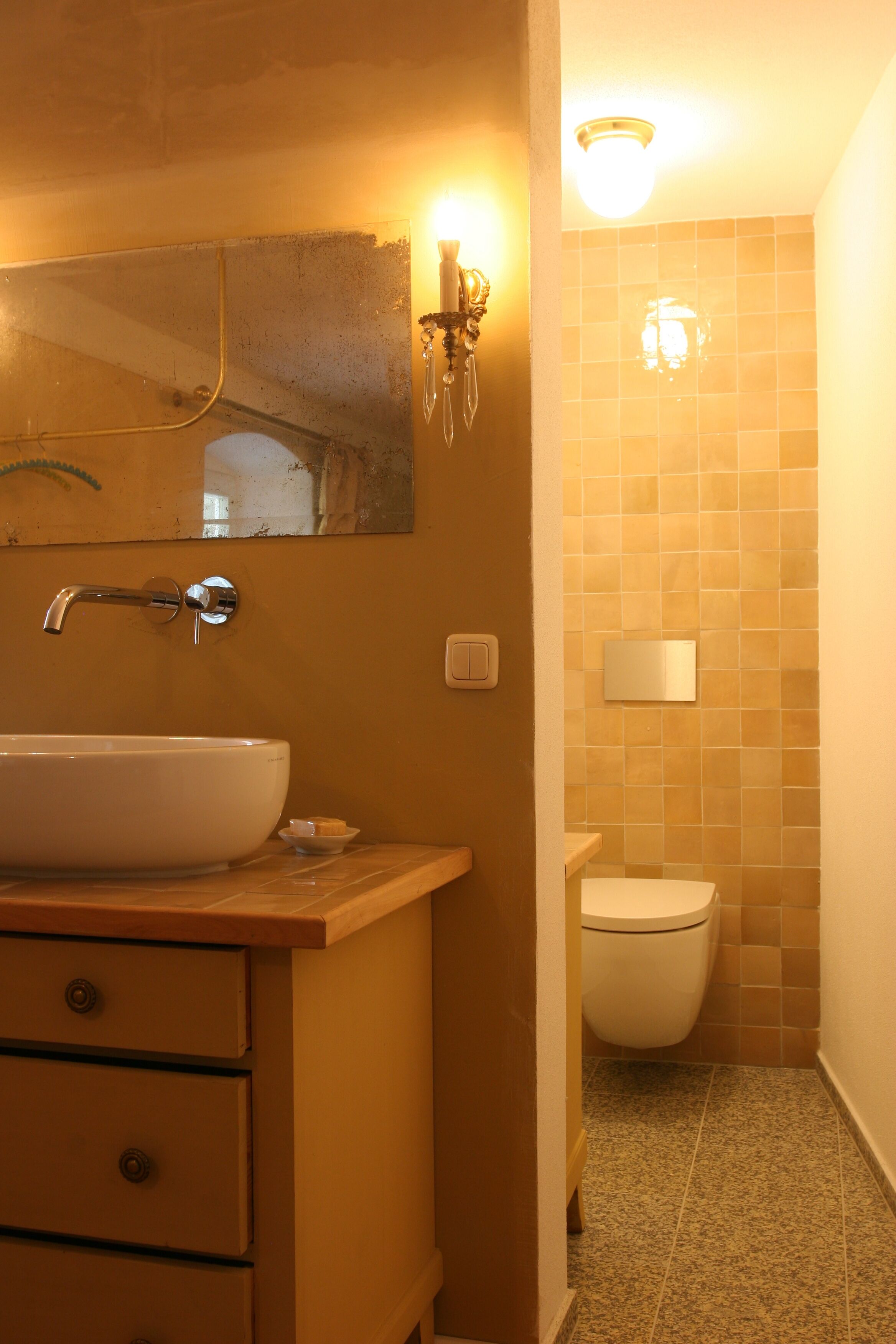 A bathroom with a white sink, a mirror, a light fixture, and a toilet.