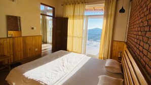 Una camera da letto con un letto grande, travi in legno a soffitto, un muro in mattoni e vista sull'esterno.