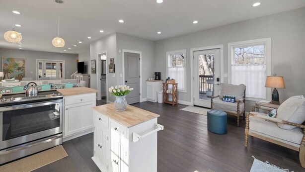 A spacious kitchen with modern appliances, a dining area with a wooden table, and a cozy seating area with a lamp.