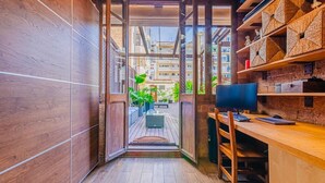 Un pasillo estrecho con piso de madera que lleva a un balcón con mobiliario exterior.