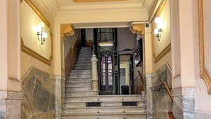Un magnifique escalier en marbre, orné de motifs dorés complexes, menant à une porte sombre.