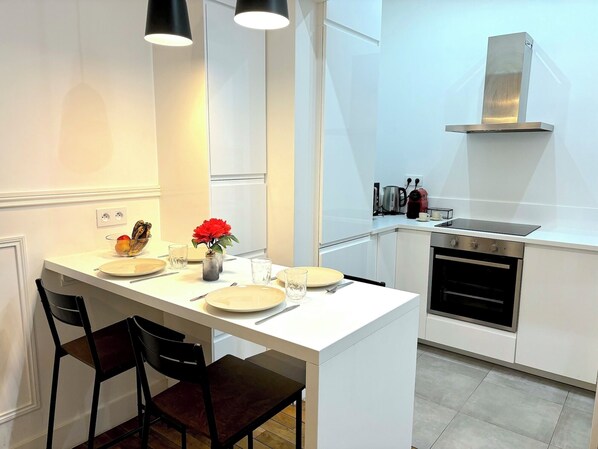 A modern kitchen with white cabinetry, a built-in oven, and a stainless steel range hood.