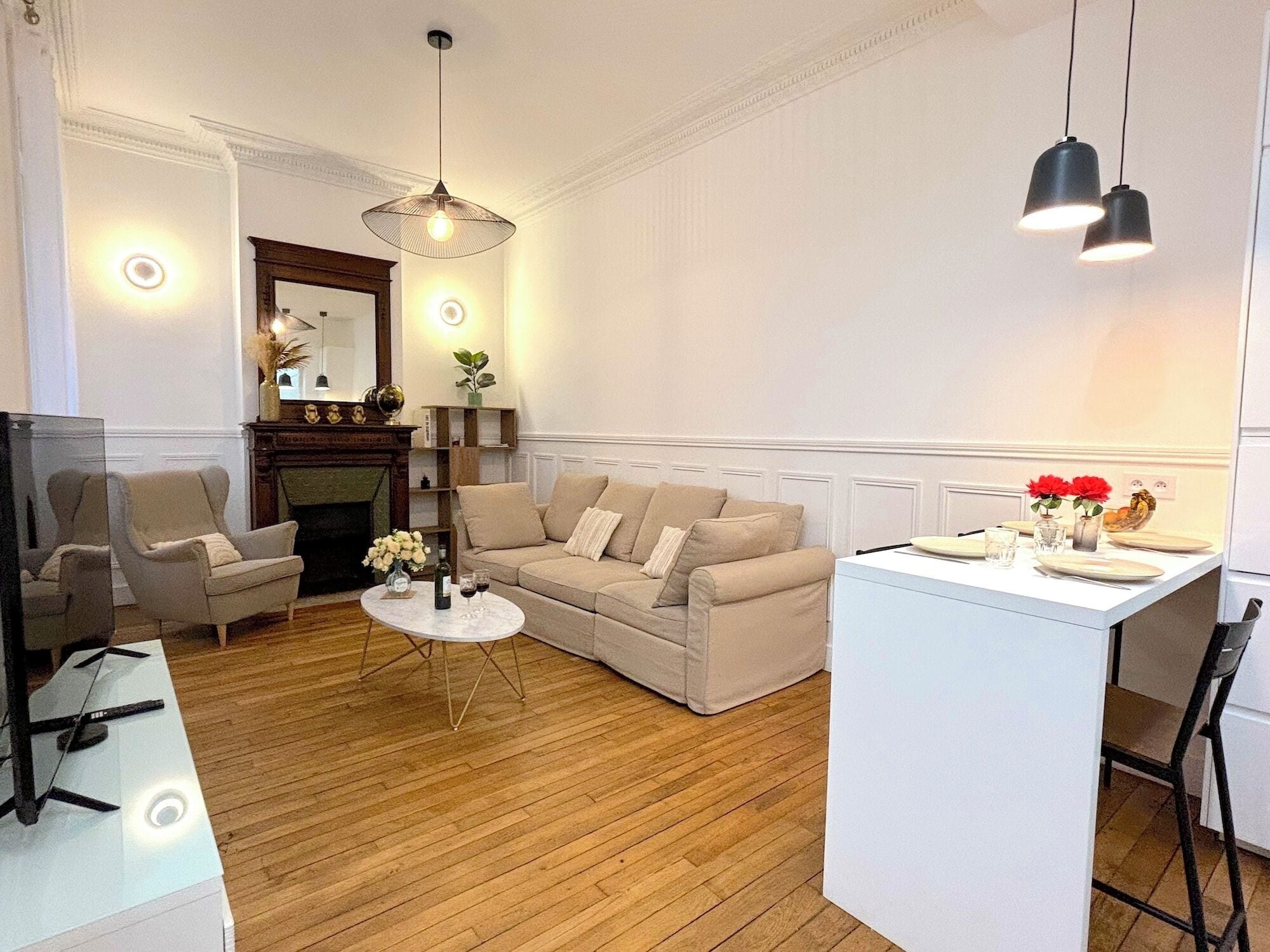 A living room with a sofa, armchairs, a coffee table, and a fireplace. There is a dining area with a table set for two.