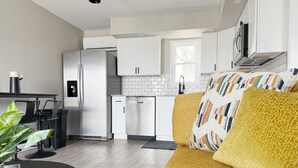Eine moderne Küche mit weißen Schränken, einem Edelstahlkühlschrank und einem eingebauten Backofen.