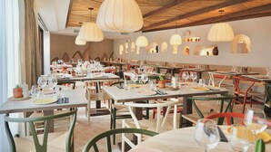 A restaurant with multiple tables and chairs, wooden ceiling beams, and pendant lights. - Roc Seven Biarritz (Biarritz)