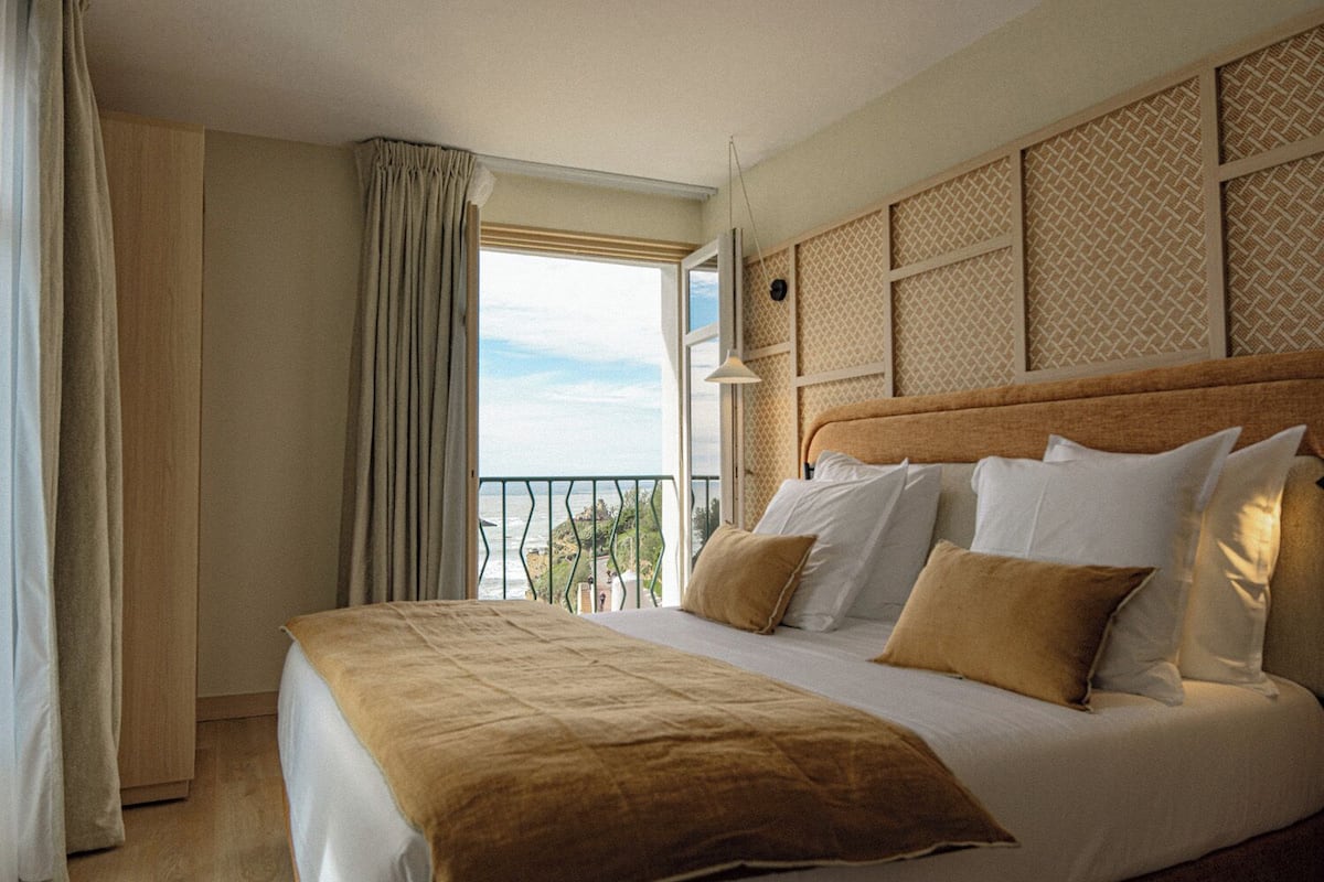 A hotel room with a large bed, a view of the sea, and a balcony.