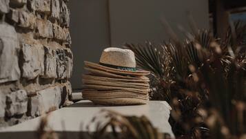 A stack of hats on a ledge with a stone wall and dried plants in the background.