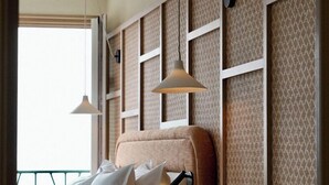 A neatly arranged hotel room with a bed, pillows, a bedside table, and a hanging lamp. - Roc Seven Biarritz (Biarritz)