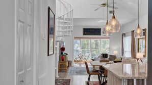 Una cocina moderna con una isla central, iluminación colgante y vistas al área de comedor.