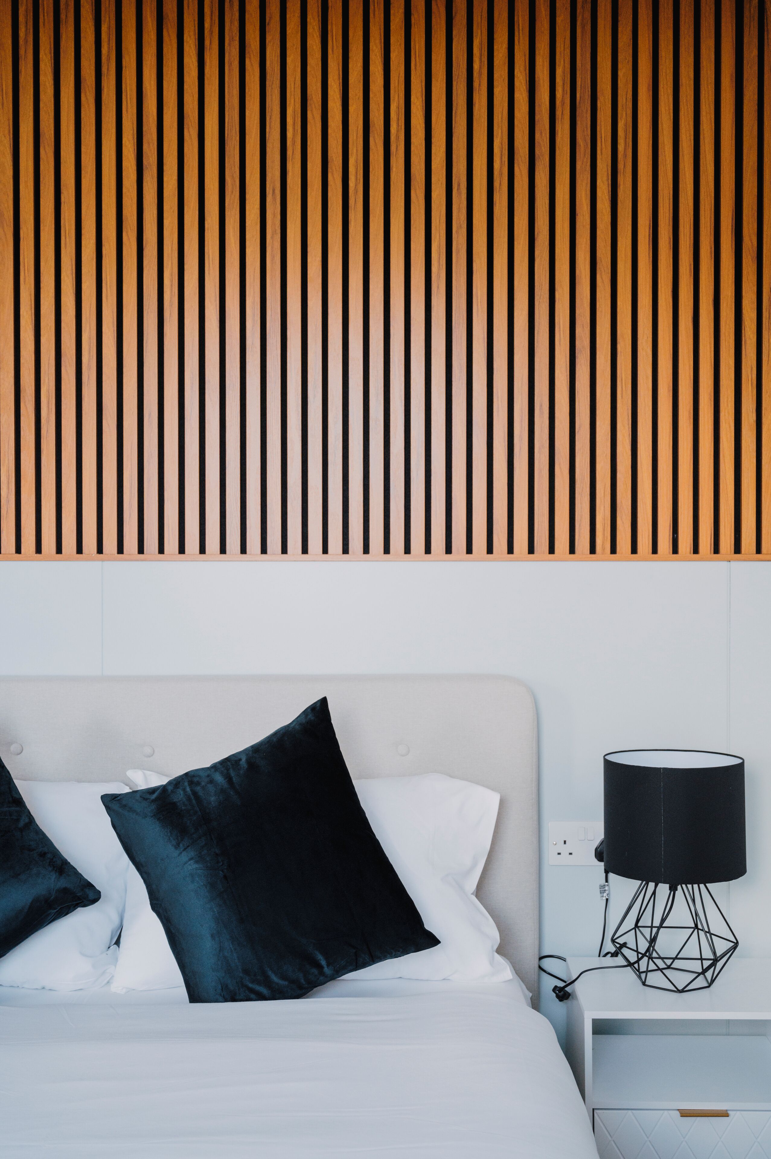 Une chambre à coucher avec un lit, des oreillers, une table de chevet et une lampe.