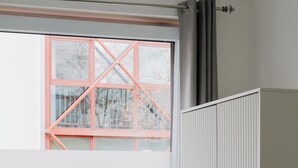 A room with a large window, a radiator, a white wardrobe with gold handles, and a white armchair. - WNS Hotel (London)