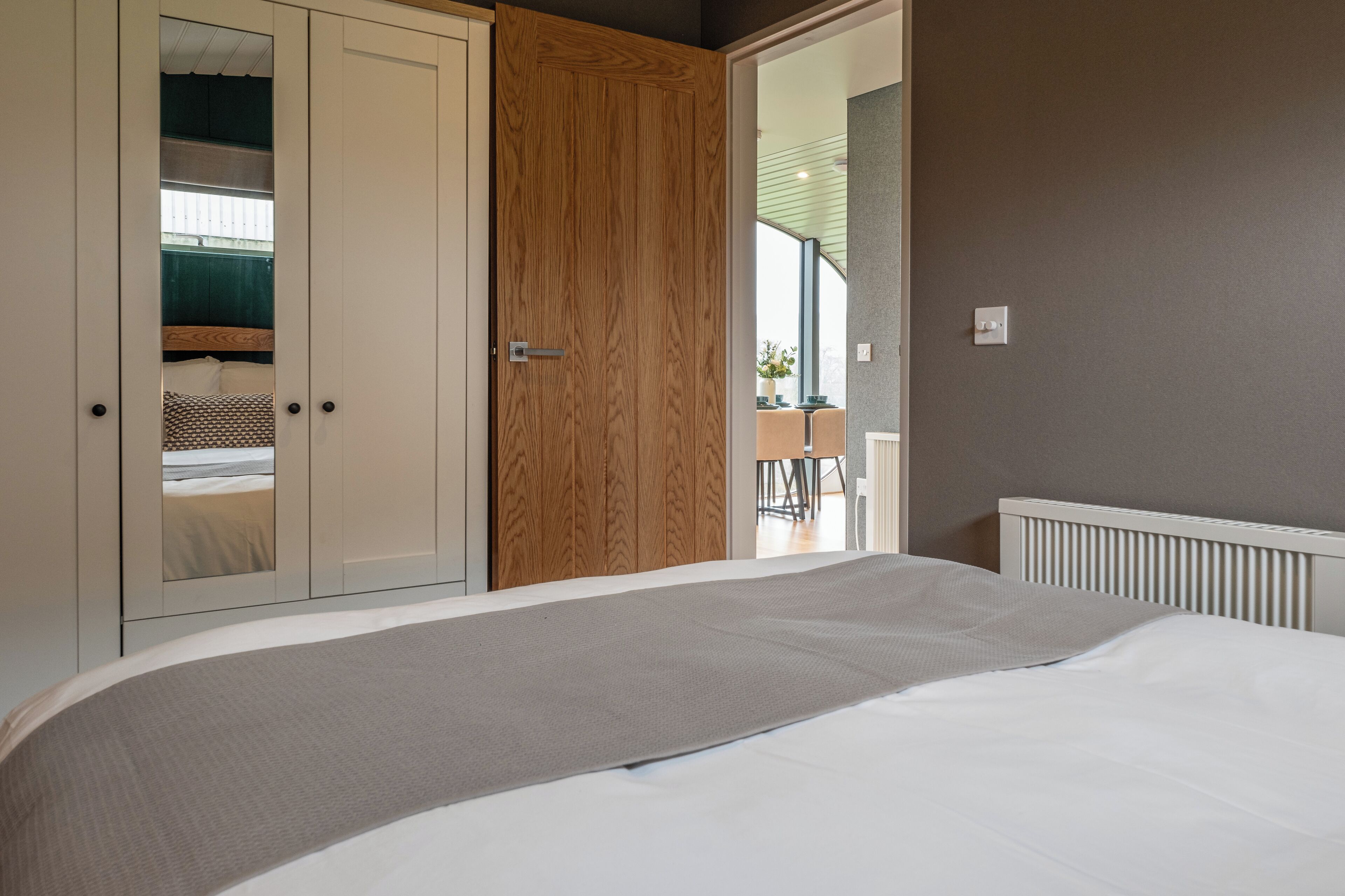 A bedroom with a bed, a wardrobe, and a door leading to another room.