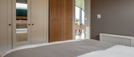 A bedroom with a bed, a wardrobe, and a door leading to another room.