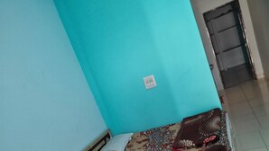 A bedroom with a bed, a door, and a wall socket.
