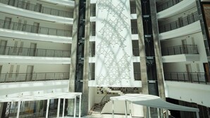 A multi-level atrium with a glass dome ceiling, multiple balconies, and a central elevator shaft.