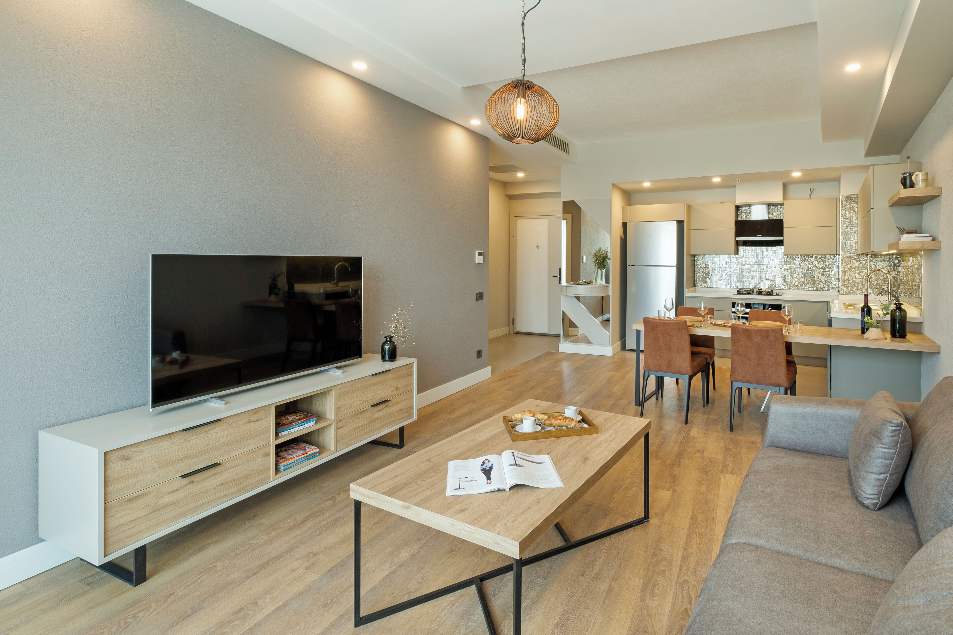 A modern living room with a flat-screen TV, wooden coffee table, and a sofa.