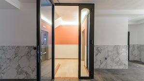 Un interior moderno con una puerta de cristal que da a una habitación con un muro naranja.