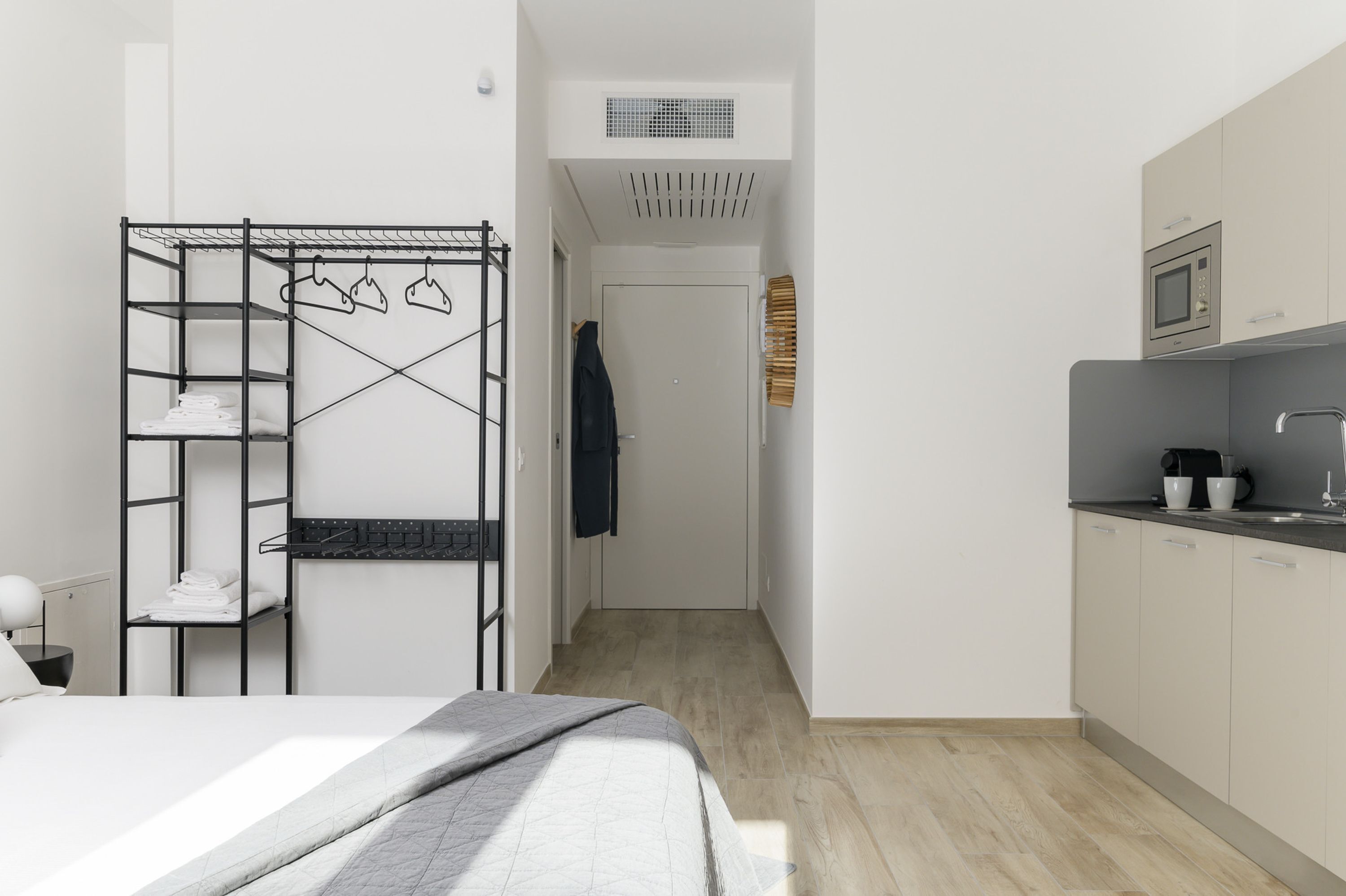 A compact hotel room with a bunk bed, a kitchenette, and a door leading to a bathroom.
