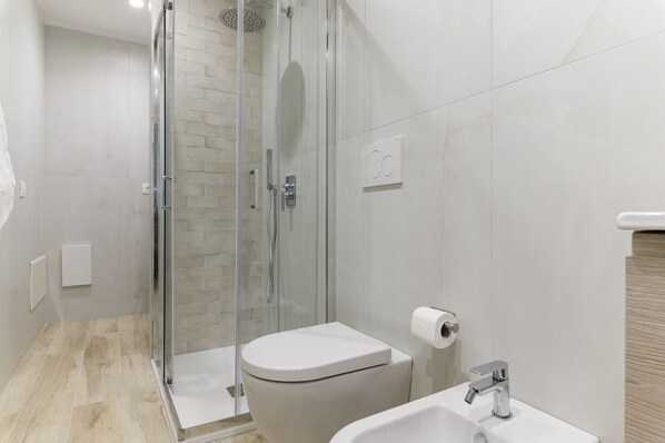 A modern bathroom with a glass shower enclosure, a toilet, and a sink.
