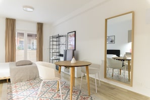 A hotel room with a bed, a round table with chairs, a large mirror, and a window with curtains.