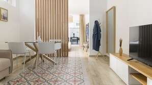 A modern living room with a TV, a sofa, a dining area with a table and chairs, and a patterned rug. - Palazzo Murat - One-bedroom Apartment With Terrace by Wonderful Italy (Bari)