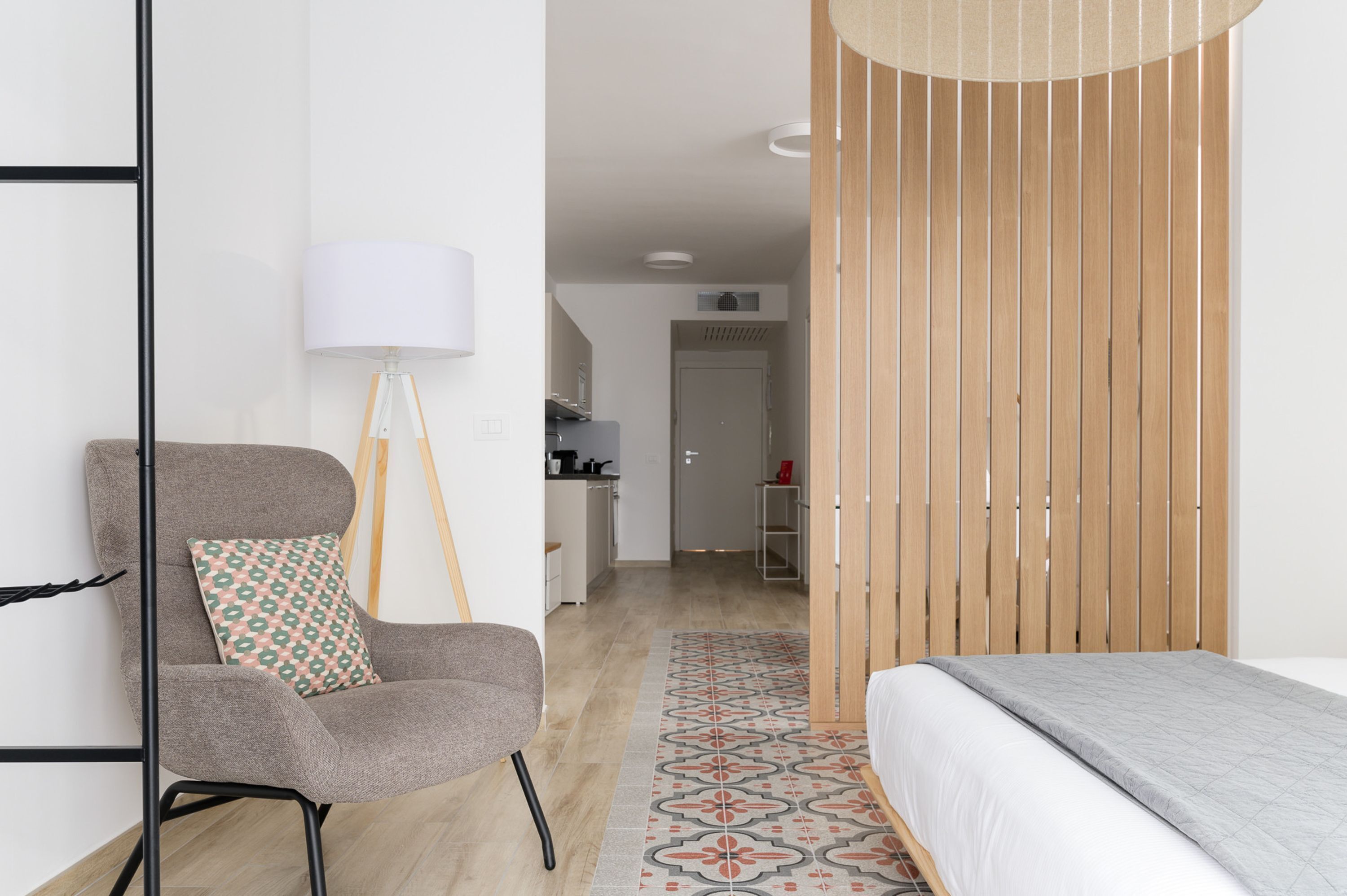 A modern bedroom with a bed, a chair, a lamp, and a wooden wardrobe.