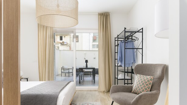 A hotel room with a bed, a chair, a table, and a view of the outside. - Palazzo Murat - One-bedroom Apartment With Terrace by Wonderful Italy (Bari)