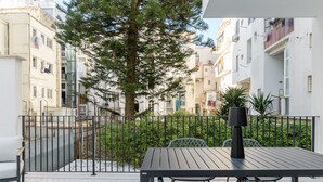 A balcony with a table and chairs, surrounded by a metal fence and greenery. - Palazzo Murat - One-bedroom Apartment With Terrace by Wonderful Italy (Bari)