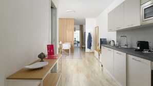 A modern kitchen with a wooden table, a white chair, and a kitchen island. - Palazzo Murat - One-bedroom Apartment With Terrace by Wonderful Italy (Bari)