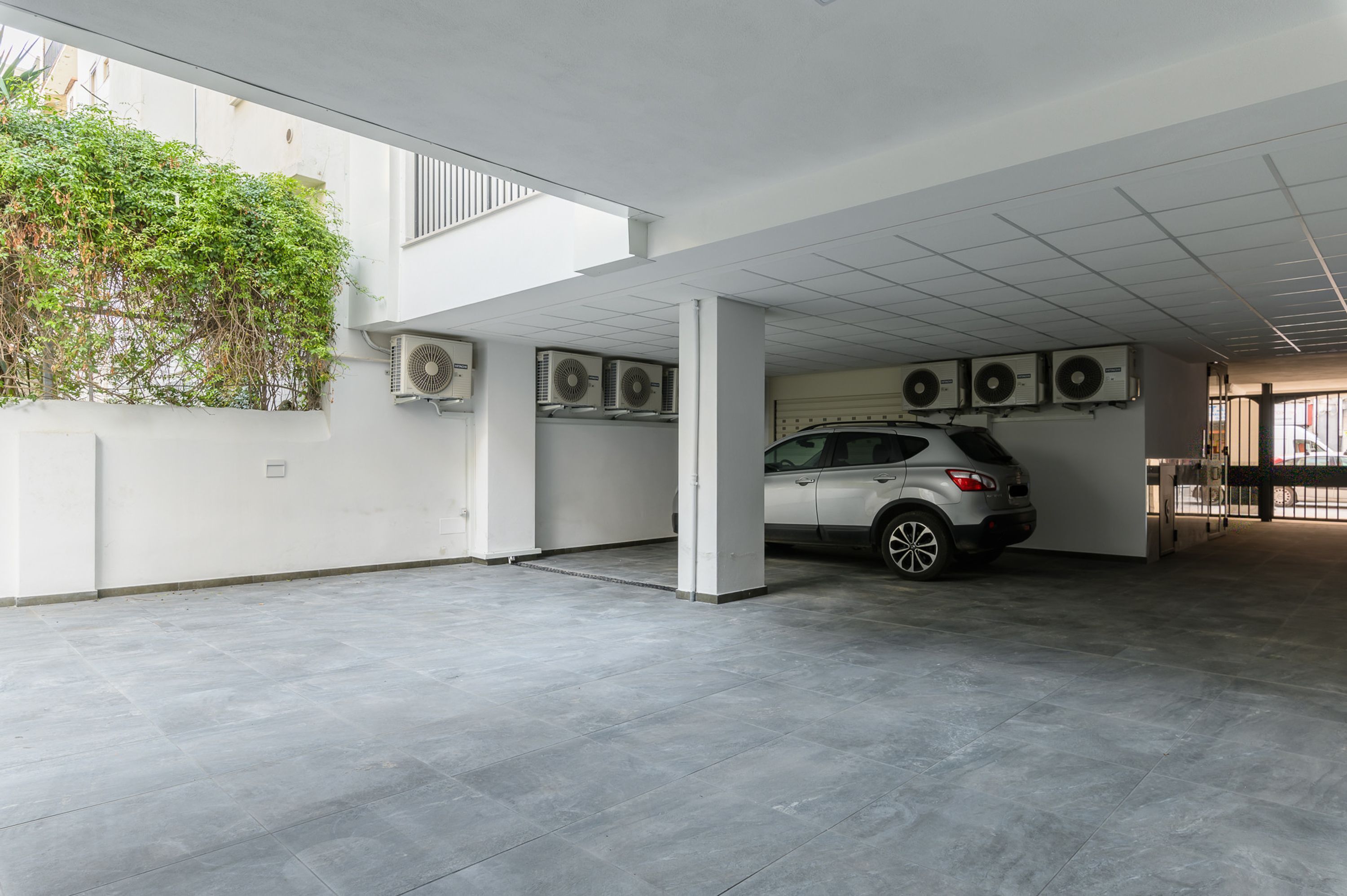 An empty parking garage with a white car parked in one of the spaces.