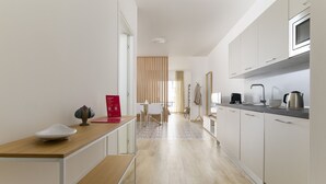 A modern kitchen with white cabinets, a wooden countertop, and a dining area with a table and chairs. - Palazzo Murat - One-bedroom Apartment With Balcony by Wonderful Italy (Bari)