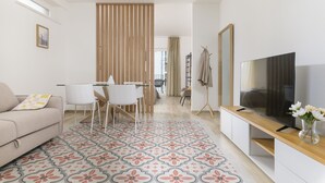 A modern living room with a sofa, dining table, chairs, a TV, and a patterned rug. - Palazzo Murat - One-bedroom Apartment With Balcony by Wonderful Italy (Bari)