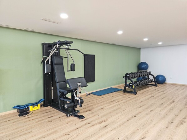 Un gimnasio con equipo de ejercicio, una colchoneta azul y un espejo montado en la pared.